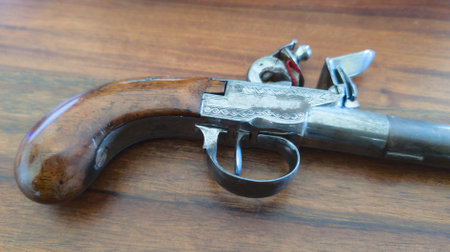 old ancient antique gun with openwork wood carvings and handle firearm pistol weapon on wooden backgroundの写真素材