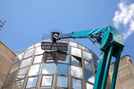 washing building forklift lifting platform in street in front of facade of glass building to clean...