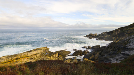 rocky coast atlantic ocean in cloudy weather with sea water waves and foam natureの写真素材