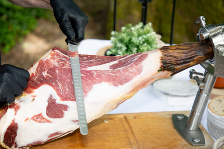professional man hands chef slicing iberico spanish pork cured ham cutting ham during an event party tableの写真素材
