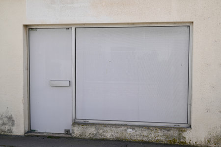 shop closed due to lack of business and bankruptcy in the city shopping street with the facade painted whiteの写真素材