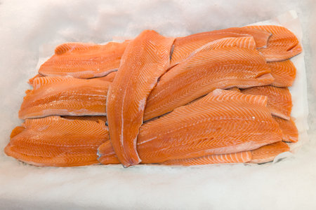 fresh salmon seafood on crushed ice at fish market raw fillet on display counter at store in concept...