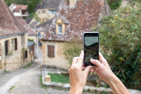 pov woman hand holding touch screen smart phone on blurred old tourism city building backgroundの写真素材