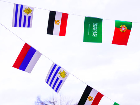 flags of countries international bunting flag hanging against a cloudy sky for uruguay egypt saudi arabia portugalの写真素材