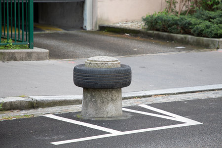 concrete bollard with old tire guarding a car parking space recycled tire as park protectorの写真素材