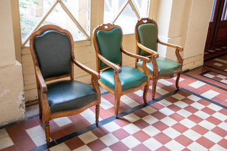 three vintage armchairs with green leather upholstery on tiled floor in old world waiting roomの写真素材