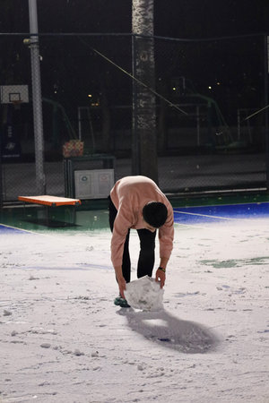 Young man playing ice hockey at night on the ice rink in winterの写真素材
