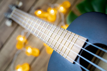 Wooden ukulele on wooden background with pineapple shaped tropical lightsの写真素材