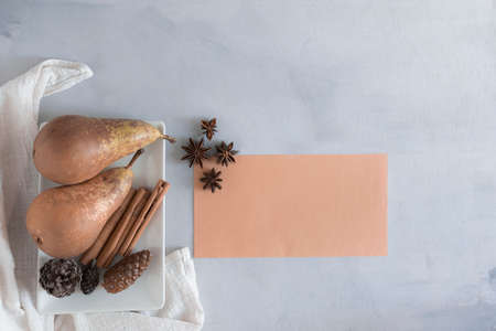 Table set with pears, star anise, pine cones, cinnamon sticks and a blank card with copy space. Top view and bright, soft-colored photographyの写真素材