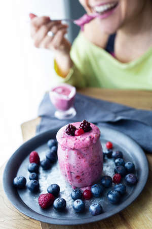 Girl drinking a red berry smoothie. Red fruit smoothie with vegetable milk. Vegetarian smoothies. Perfect breakfast for plant-based diet. Food photographyの写真素材