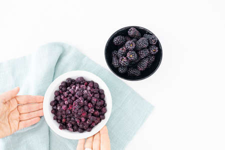Bowl with fresh blackberries and bowl with frozen blueberries. Fresh or frozen fruit. Berries source of antioxidants and vitaminsの写真素材