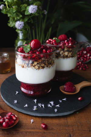 Yogurt parfait with red fruits. Dessert based on yogurt, raspberries and pomegranate. Healthy sweet dessertの写真素材