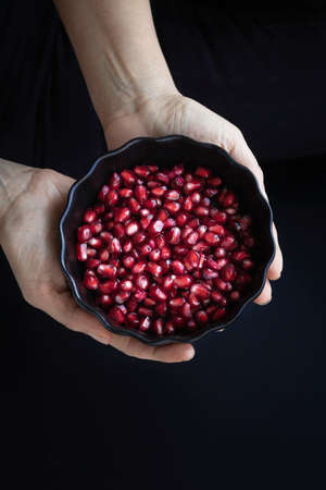 Pomegranate seeds. Woman's hands holding a bowl with pomegranate seedsの写真素材