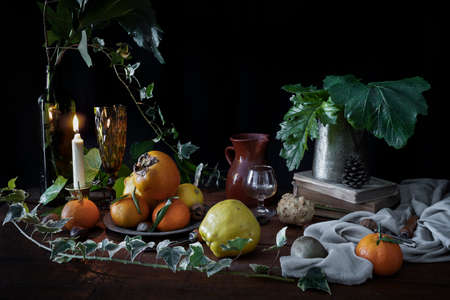 Still life with autumn and winter fruits. Dark mood still life with fruits and green leaves. Baroque style still lifeの写真素材