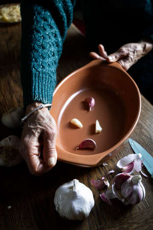 Woman's hand holding a baking tray with garlic. Cooking with garlic. Baked garlicの写真素材