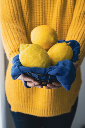Woman in yellow sweater holding some fresh lemons