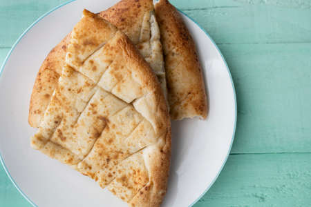 Naan, Indian flatbread, with garlic on a turquoise wooden background. traditional indian cuisineの写真素材