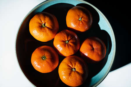 Bowl with ripe and unpeeled tangerines seen from above