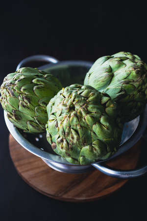 Fresh and raw artichokes on the kitchen table and with a dark backgroundの写真素材