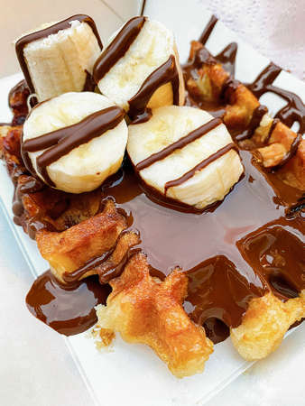 Waffle with hot dark chocolate and banana. Typical Belgian waffle