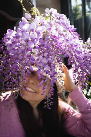 Woman hiding behind some flowering wistaria branchesの写真素材