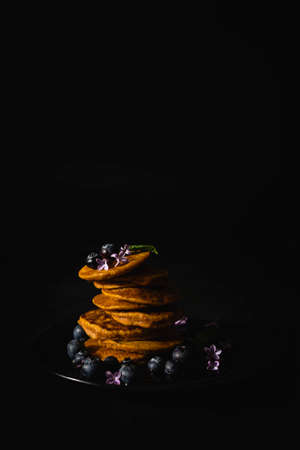 Homemade pancakes with maple syrup and fresh blueberries. Homemade and healthy breakfast with dark background. Gluten free carrot pancakesの写真素材