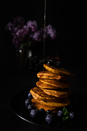 Homemade pancakes with maple syrup and fresh blueberries. Homemade and healthy breakfast with dark background. Gluten free carrot pancakesの写真素材