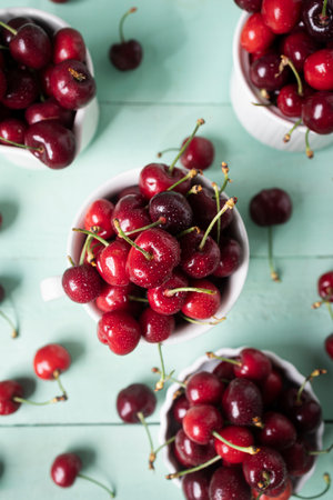 Delicious cherries in white ceramic cups on a wooden table