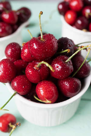 Delicious cherries in white ceramic cups on a wooden tableの写真素材