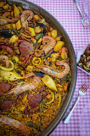 Traditional paella for the whole family. Outdoor dining with the family in the summer. Delicious traditional paella of Spanish cuisineの写真素材