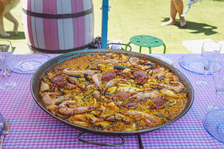Traditional paella for the whole family. Outdoor dining with the family in the summer. Delicious traditional paella of Spanish cuisineの写真素材