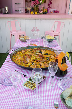 Traditional paella for the whole family. Outdoor dining with the family in the summer. Delicious traditional paella of Spanish cuisineの写真素材