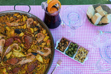 Traditional paella for the whole family. Outdoor dining with the family in the summer. Delicious traditional paella of Spanish cuisineの写真素材
