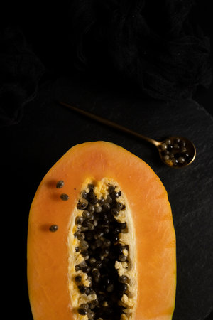 Ripe and freshly cut papaya. Fresh and tropical fruit with dark backgroundの写真素材