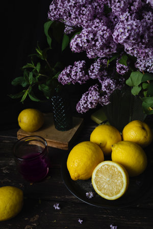 A bouquet of lilacs sits on a table with lemons.の写真素材