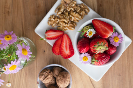 Strawberries with walnuts and daisies on wooden tableの写真素材