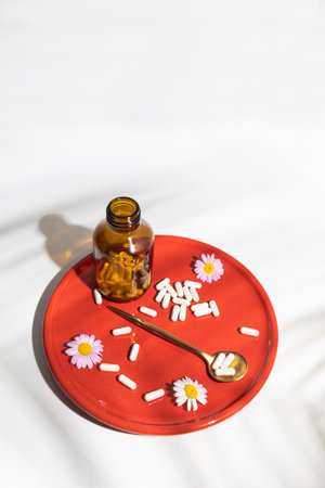 medicine bottle with chamomile on a red plateの写真素材