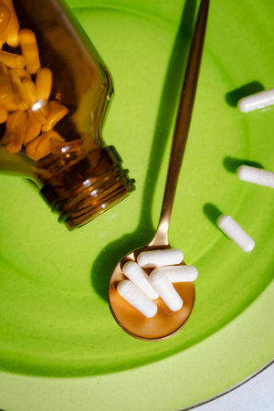 White pills, supplements, vitamins... White tablets and pills pouring out of a medicine bottle. Macro view from above with copy space.の写真素材