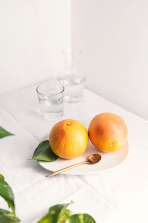 Ripe juicy grapefruits on a white plate on a white backgroundの写真素材