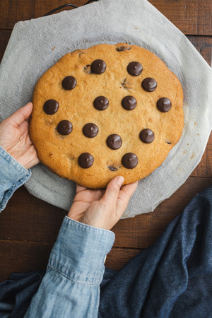 Giant chocolate chip cookie. Large and delicious homemade cookie with chunks of dark chocolate. The perfect breakfast or snack for those with a sweet toothの写真素材