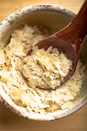 Close-up of a bowl and a wooden spoon with nutritional yeast, excellent vegan proteinの写真素材