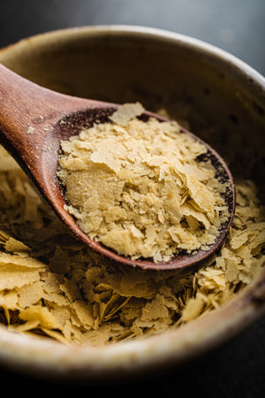 Close-up of a bowl and a wooden spoon with nutritional yeast, excellent vegan proteinの写真素材