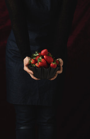 Delicious, ripe, red strawberries in a metallic bowl against a black backgroundの写真素材