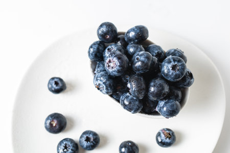 Fresh blueberries in a white bowl on a white background, with room for textの写真素材