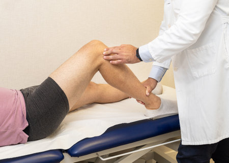 A traumatologist examining a patient's leg on a table during a clinical consultation