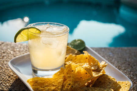 A close-up of lemon ginger kombucha and nachos on a plate by the pool, perfect for a summer day.の写真素材