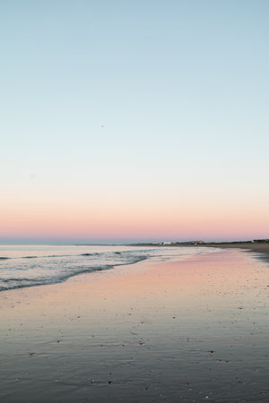 Serene sunrise at Playa de los Enebrales, Huelva, with pastel pink skies and turquoise waters creating a peaceful sceneの写真素材