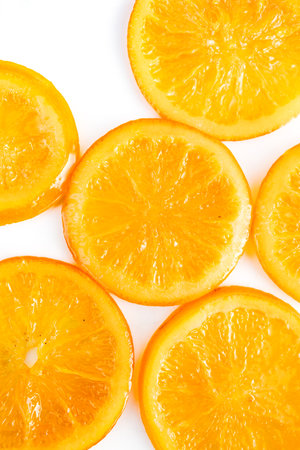 Vibrant candied orange slices displayed on a white ceramic plateの写真素材