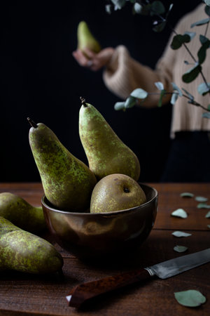 fresh conference pears arranged on a wooden table, contrasting beautifully with the deep dark background.の写真素材