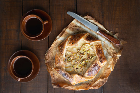 A mouthwatering pear, cheese, and honey galette served on a rustic wooden table, showcasing its golden crust and gourmet ingredients.の写真素材